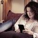 Woman lying on a sofa with iPhone 7 smartphone... (thumbnail)
