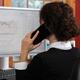 Woman stock trader speaking on the phone at a computer... (thumbnail)