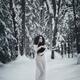 Woman in white dress walking in snow with a black cat in her hands... (thumbnail)