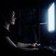 Woman sitting in dark in front of a computer screen... (thumbnail)