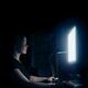 Young woman sitting at night in front of a computer display... (thumbnail)