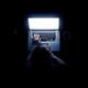 Woman sitting in light of laptop screen at a desk... (thumbnail)