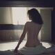 Woman sitting in bathroom undressed back view... (thumbnail)