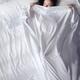 Young woman in bed peeking from under a blanket... (thumbnail)