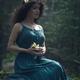 Beautiful woman in green dress sitting in the nature with a flower in... (thumbnail)