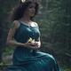 Beautiful woman in green dress in the nature with a flower in her hand... (thumbnail)