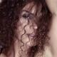 Sultry beauty face portrait of young woman looking through her long cu... (thumbnail)