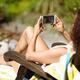 Woman in chaise lounge sunbathing with an iPhone in her hands... (thumbnail)