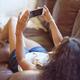 Woman lying on a sofa watching video on iPhone smartphone... (thumbnail)