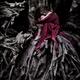 Woman in red dress curled up like a child in roots of an old dead tree... (thumbnail)