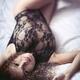 Sensual boudoir portrait of a smiling young woman lying on bed in lacy... (thumbnail)