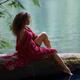 Young woman sitting on a tree in the nature with thoughtful expression... (thumbnail)