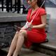 Woman in red dress sitting on the street under umbrella with cellphone... (thumbnail)