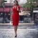 Woman in red dress with umbrella walking in the rain on a city street... (thumbnail)