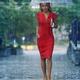Young woman in red elegant dress with umbrella walking thoughtfully in... (thumbnail)