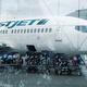 Luggage carrier train by WestJet airplane at an airport... (thumbnail)