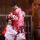 Smiling little girl and her mother dressed in red kimonos on the stree... (thumbnail)