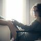 Sexy young woman in glasses sitting by the window with a book... (thumbnail)