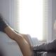 Legs of a woman sitting in a chair with a book reading by the window... (thumbnail)