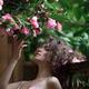 Portrait of a woman standing under a beautiful blooming camellia tree... (thumbnail)