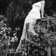 Young woman in a summer dress sitting on blacony railings in a garden... (thumbnail)