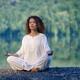 Woman in white clothes meditating in the morning sunrise by the lake... (thumbnail)