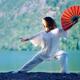 Woman practicing Tai Chi with a fan in sunrise in the nature... (thumbnail)