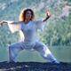 Woman in white outfit practicing Tai Chi stance by the lake in the nat... (thumbnail)