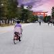 Woman on a bicycle riding towards Torii gate of Heian Shinto Shrine in... (thumbnail)
