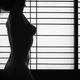 Black and white silhouette of a nude woman standing in light of glowin... (thumbnail)