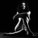 Woman sitting naked with arms and legs crossed in front of her nude bo... (thumbnail)
