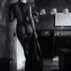 Sexy undressed woman standing by the door with a jacket in her hand Bl... (thumbnail)