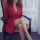 Sexy woman in red trench coat and glasses sitting in a chair with an e... (thumbnail)