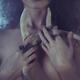 Ominous concept of beautiful mysterious woman holding deer antlers close to her bare chest