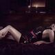 Male hands caressing a woman reclining on a bed in a sexy slick black... (thumbnail)