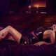 Male hands caressing a woman reclining on a bed in a sexy slick black... (thumbnail)