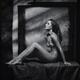 Fine art nude woman sitting naked on a posing table in artist studio... (thumbnail)