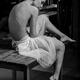 Nude woman in tutu skirt sitting thoughtfully on a table in artist stu... (thumbnail)