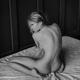 Back of a nude woman sitting insecurely on a bed... (thumbnail)