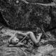Nude woman lying down curled up on the ground in a forest... (thumbnail)