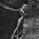 Nude woman gracefully leaning against rocks in the nature tranquil art... (thumbnail)
