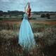 Red-haired woman in a long blue dress standing gracefully in a field o... (thumbnail)