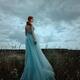 Young red haired woman in a long blue dress standing thoughtfully in a... (thumbnail)