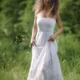 Beautiful young woman in white summer dress walking through a field of... (thumbnail)