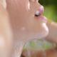 Young woman face closeup of lips in shower under fresh pouring water... (thumbnail)