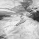 Beautiful nude woman lying in shiny water with her chest arched up and... (thumbnail)