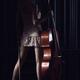 Sexy young woman standing with a cello in dark room with dramatic ligh... (thumbnail)