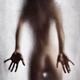 Rear view of nude sexy woman in a provocative pose standing behind wet... (thumbnail)