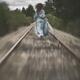 Woman running away along railroad tracks in a long dress flying in the... (thumbnail)