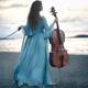 Woman in blue dress standing on a sea shore holding a cello Rear view... (thumbnail)